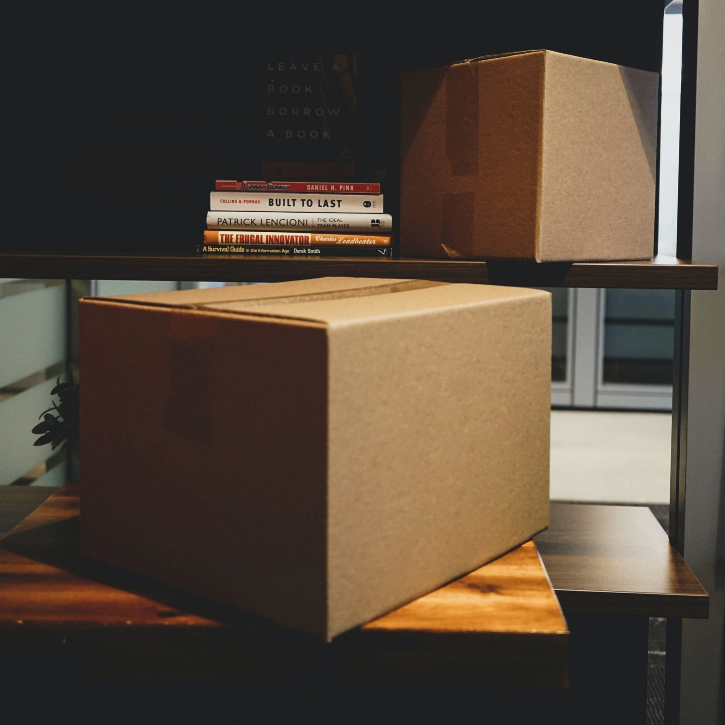 Two cardboard boxes on a wooden shelf in a home environment, indicating a product is being shipped or has been delivered.