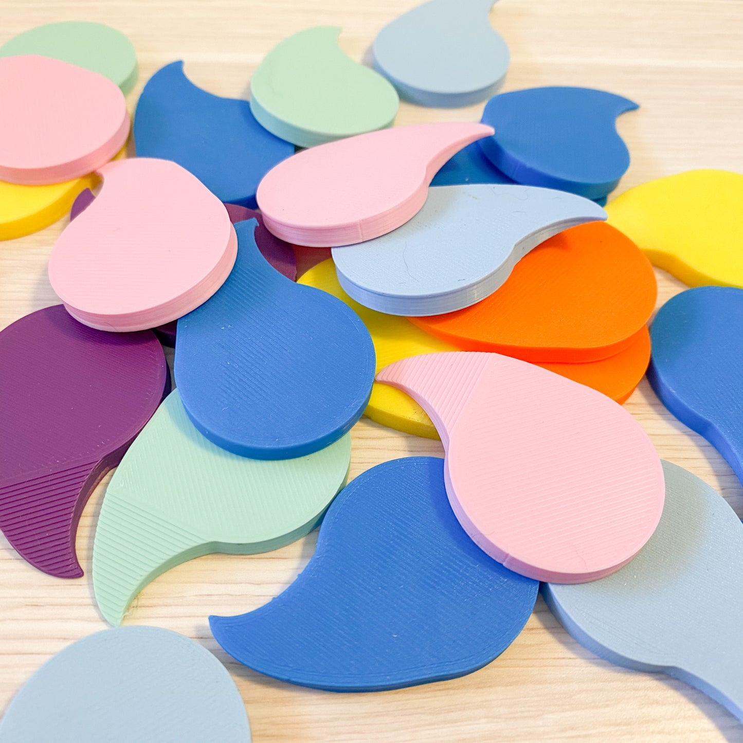 An assortment of colorful 3D printed shrink wrap openers on a surface, in various colors including blue, pink, green, purple, and orange.