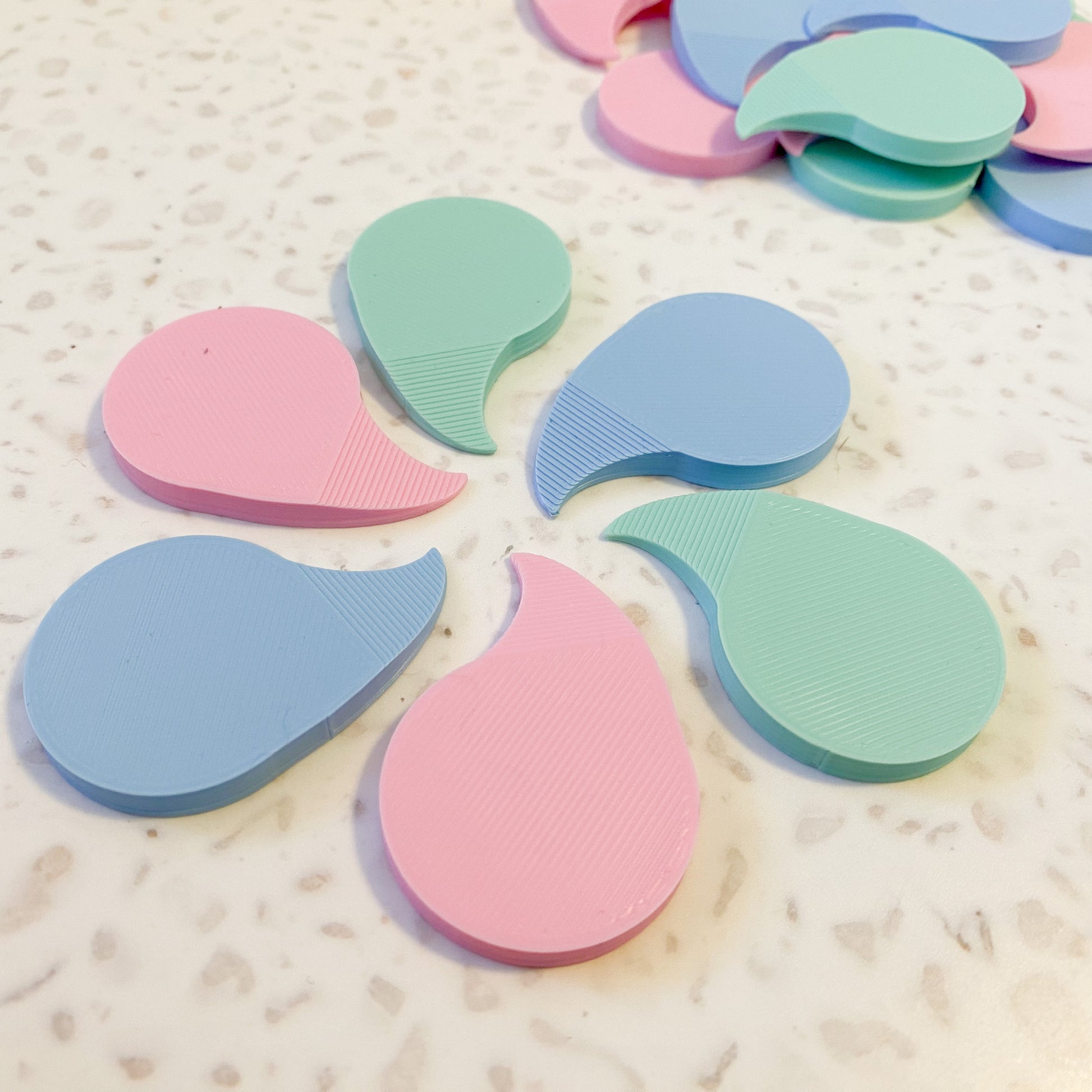 pastel coloured plastic shrink wrap openers arranged in a circle on a light speckled background