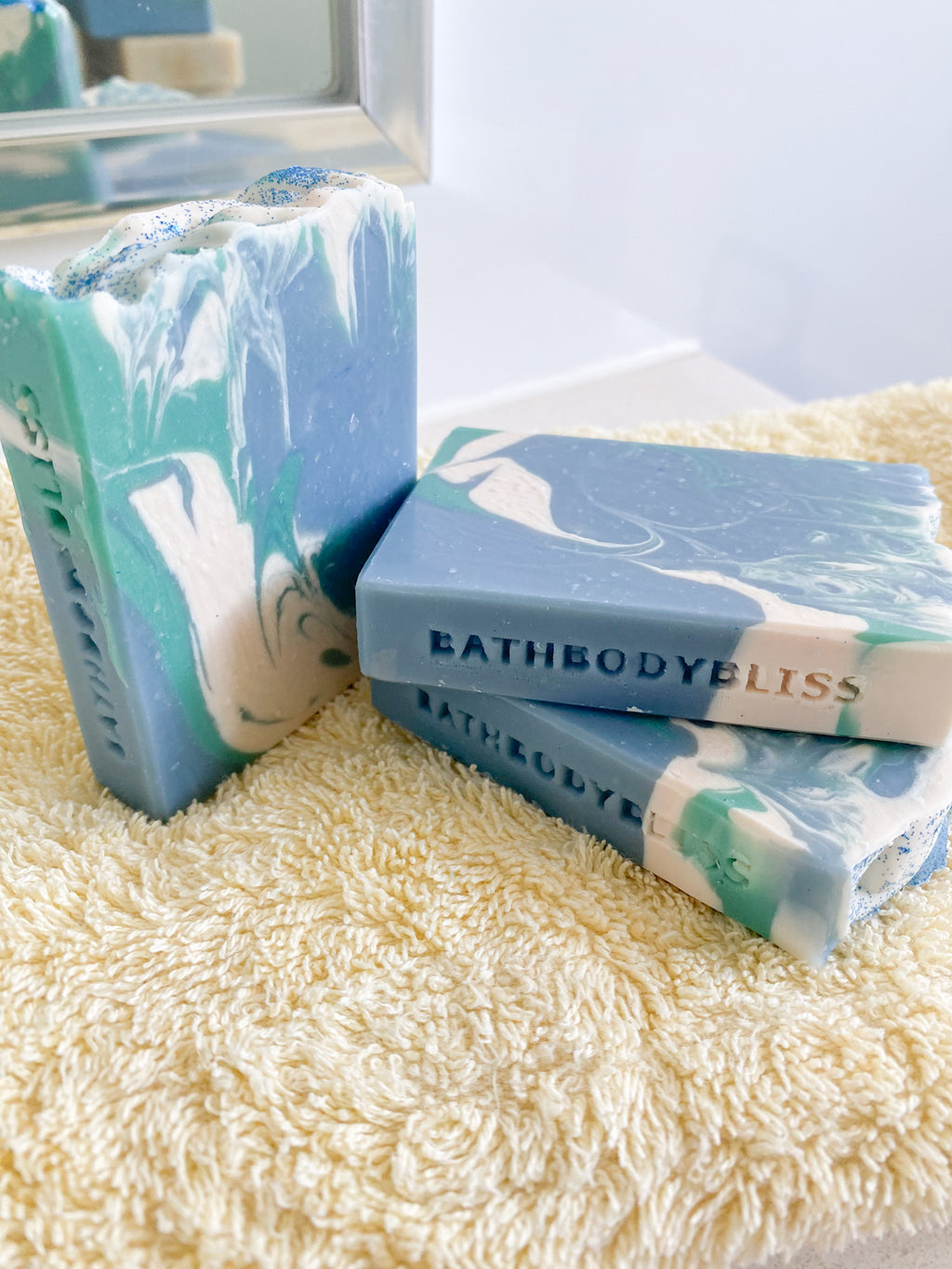 Marble-patterned soap bars with 'BathBodyBliss' branding on a textured surface.