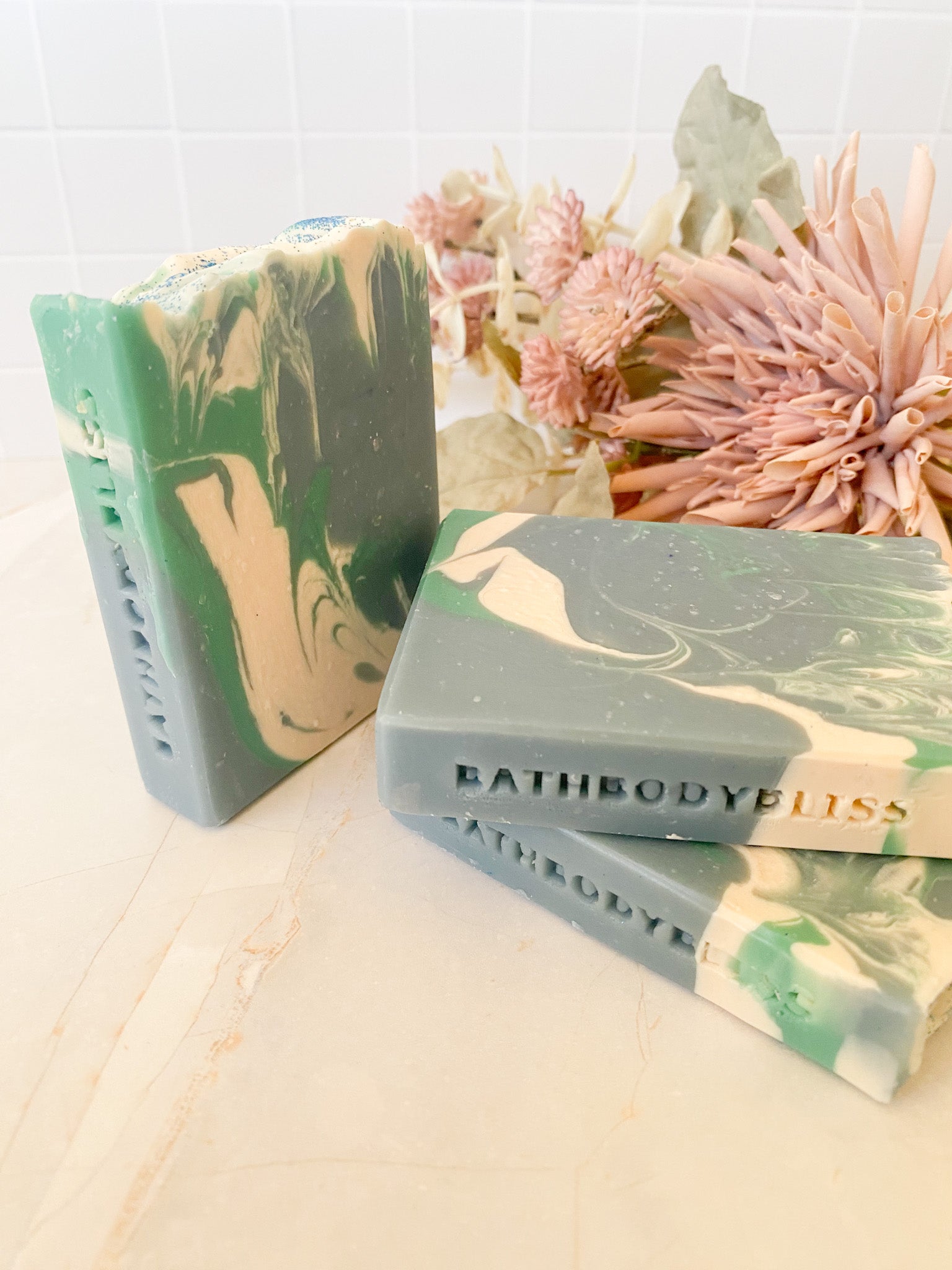 three green and white marbled soaps with 'Bathbodybliss' branding on a light surface.
