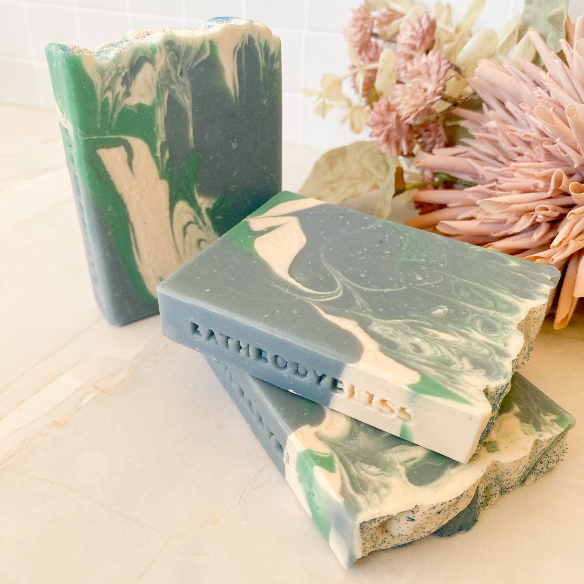 Marbled green and beige soap bars with 'Bathbodybliss' branding on a light background.