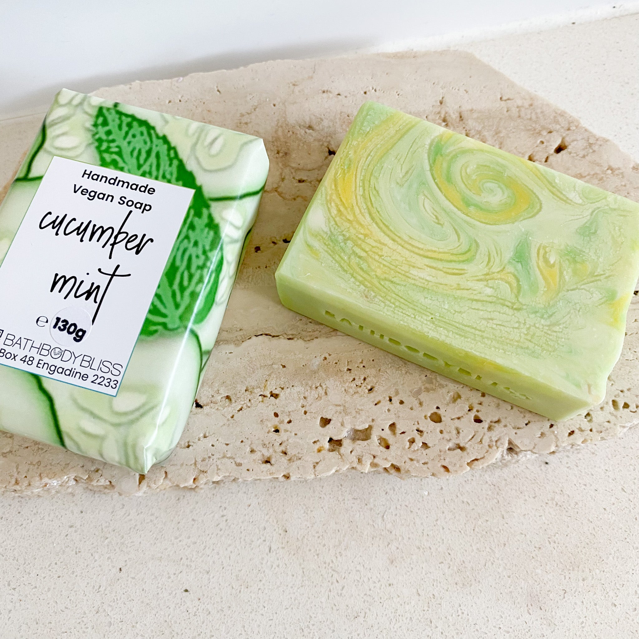 wrapped and unwrapped bars of green swirled soap on a natural rock surface