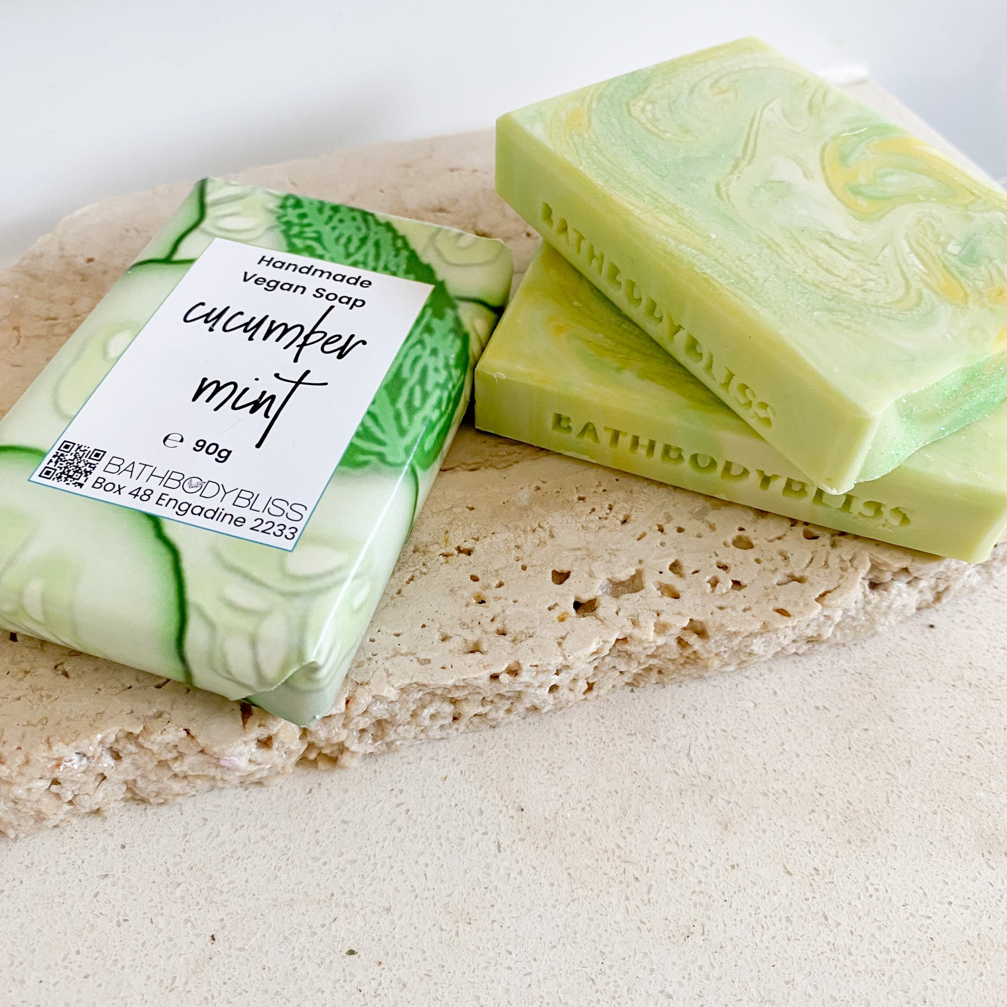 swirled green, yellow & white cucumber mint soap bars on a light rock surface