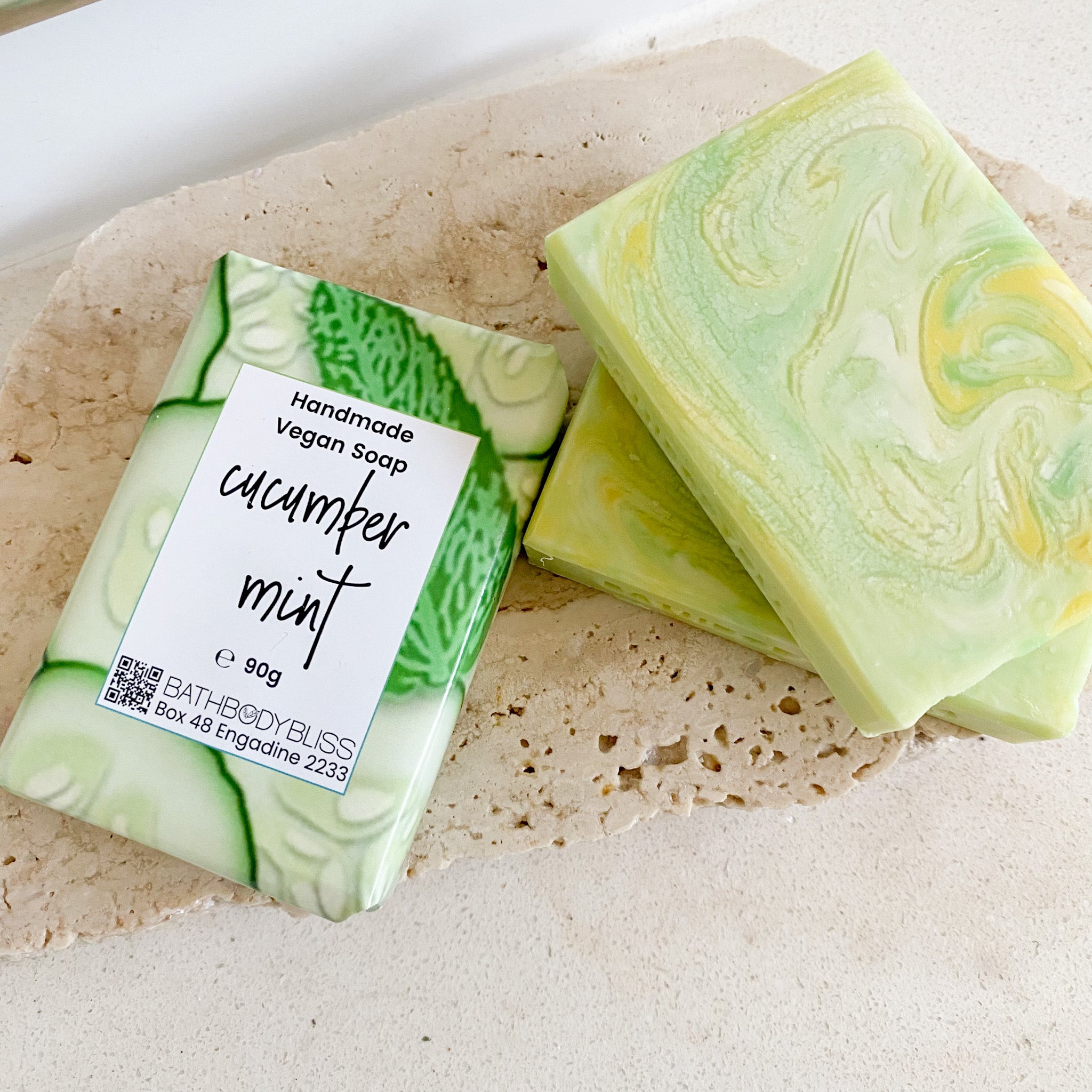swirled green, yellow & white cucumber mint soap bars on a light rock surface