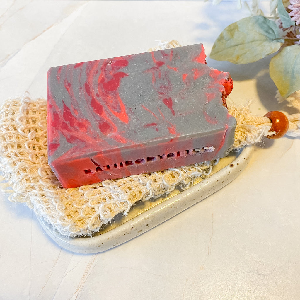 Marbled red and gray soap bar on a textured surface with 'Bathory' branding.