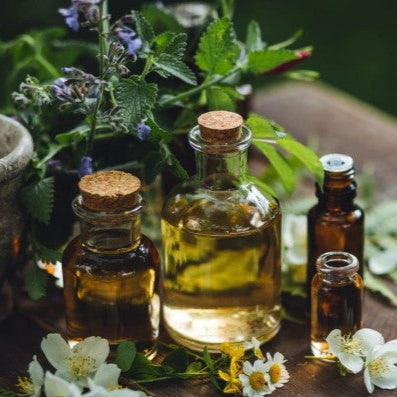 essential oils in glass bottles with cork stoppers on a wooden surface with flowers.