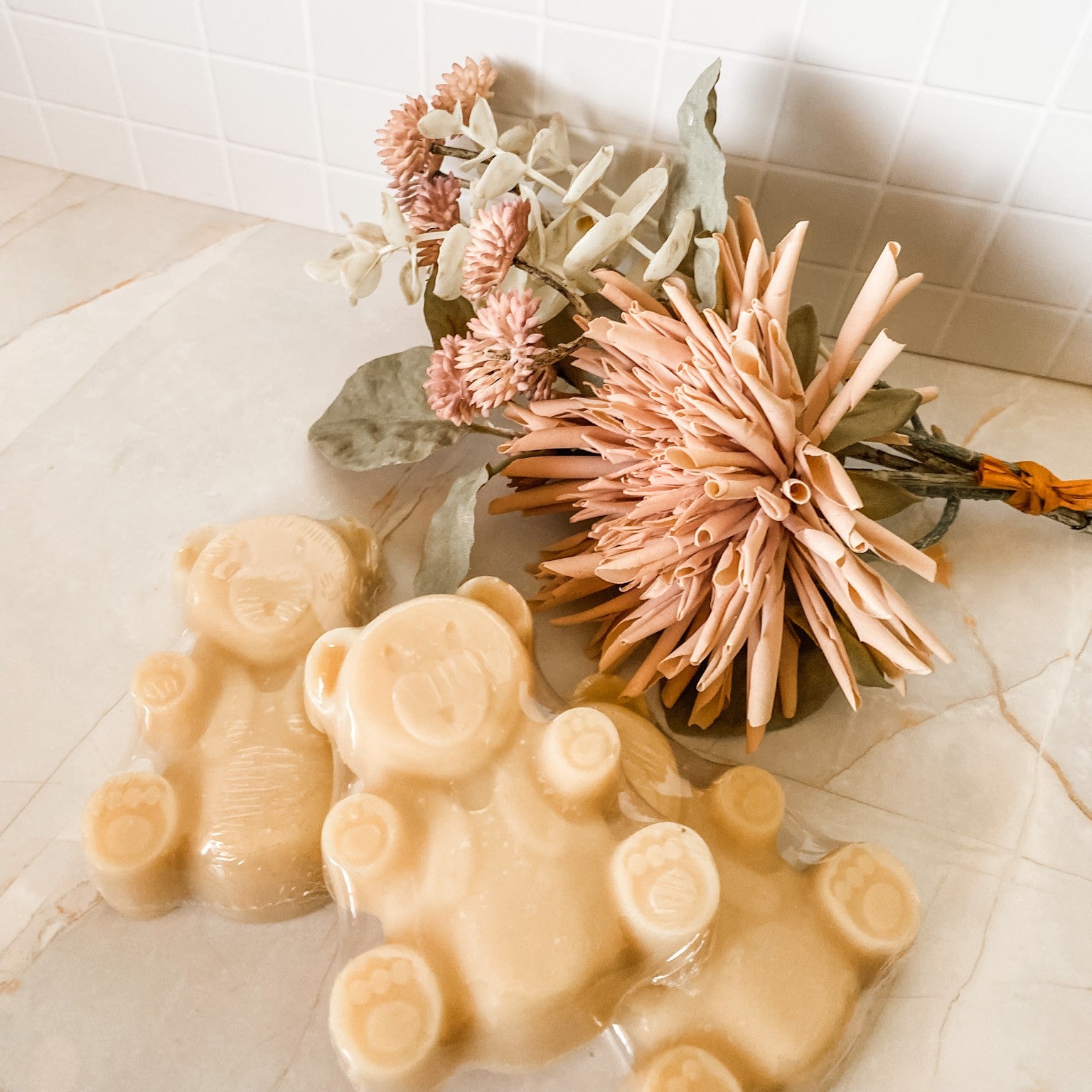 3 creamy coloured teddy bear soap bars on a marble and tile background with decorative elements