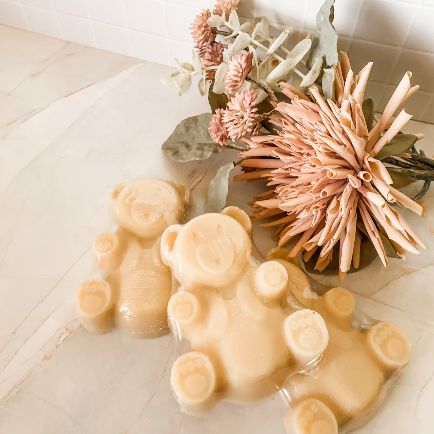3 creamy coloured teddy bear soap bars on a marble and tile background with decorative elements