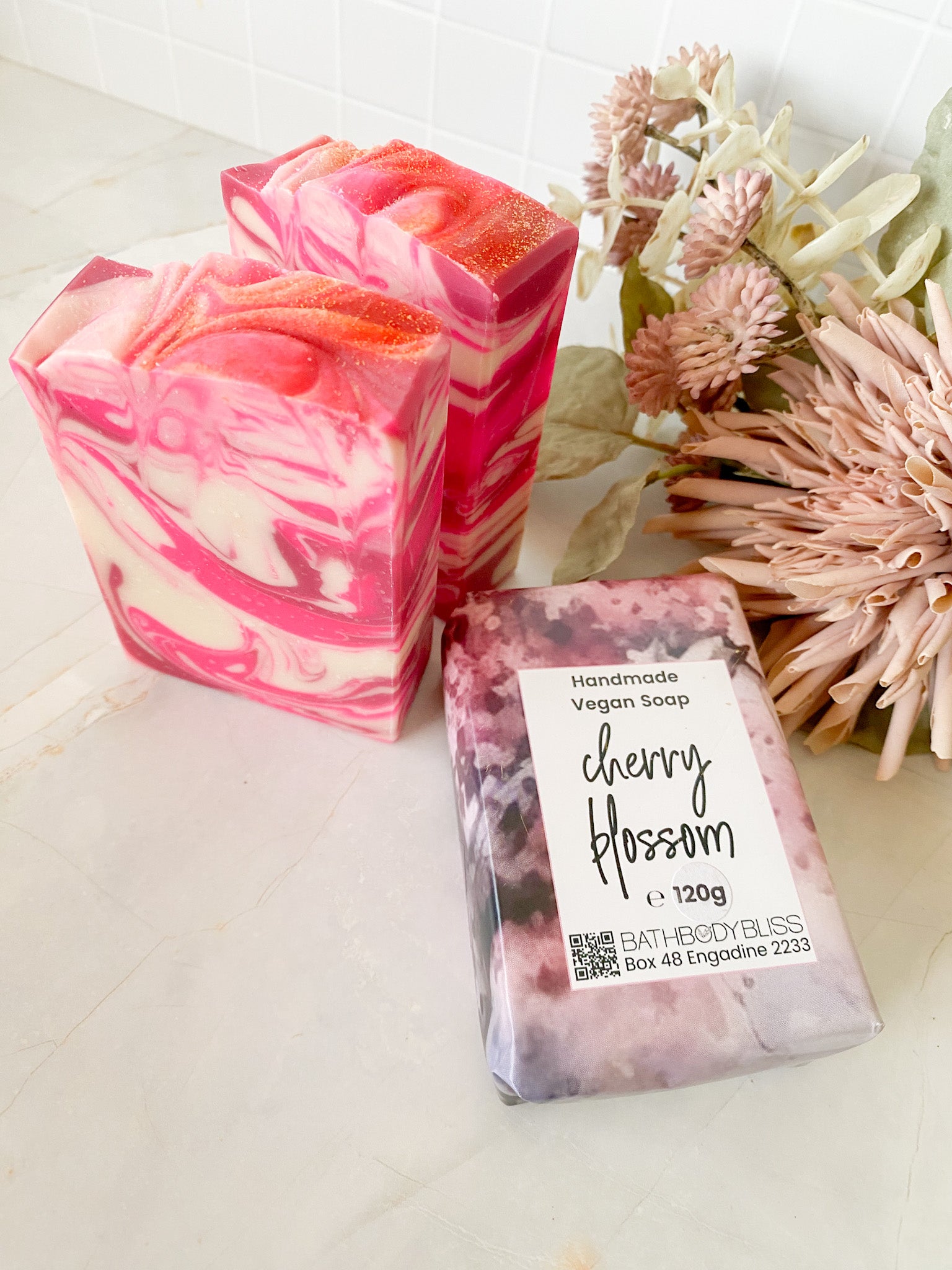 pink and white swirled cherry blossom soap bars on a light surface with floral decor