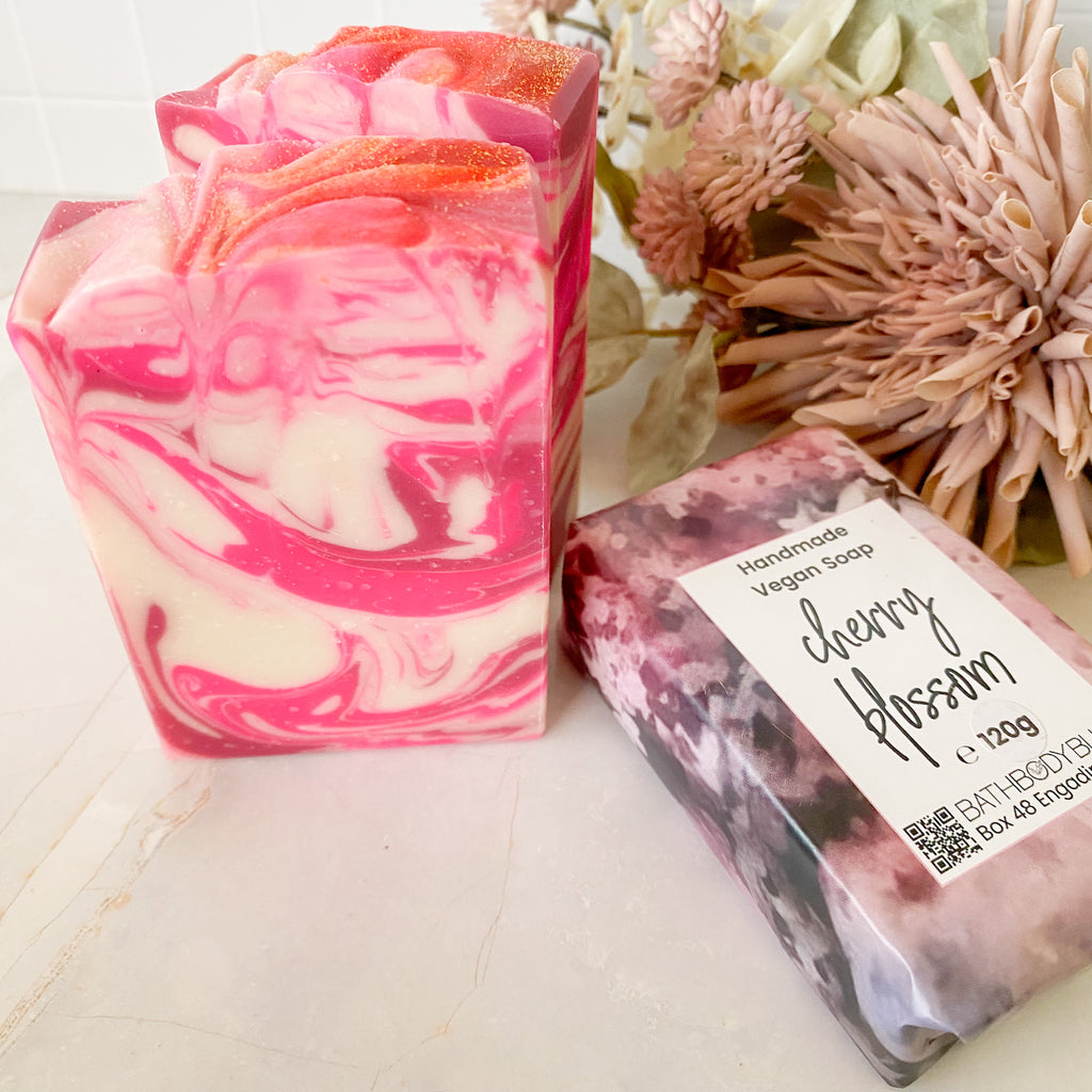 pink and white swirled soap bars on a light surface with floral decor