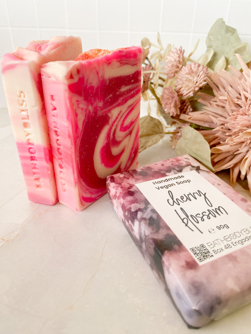 pink and white swirled soap bars on a light surface with floral decor