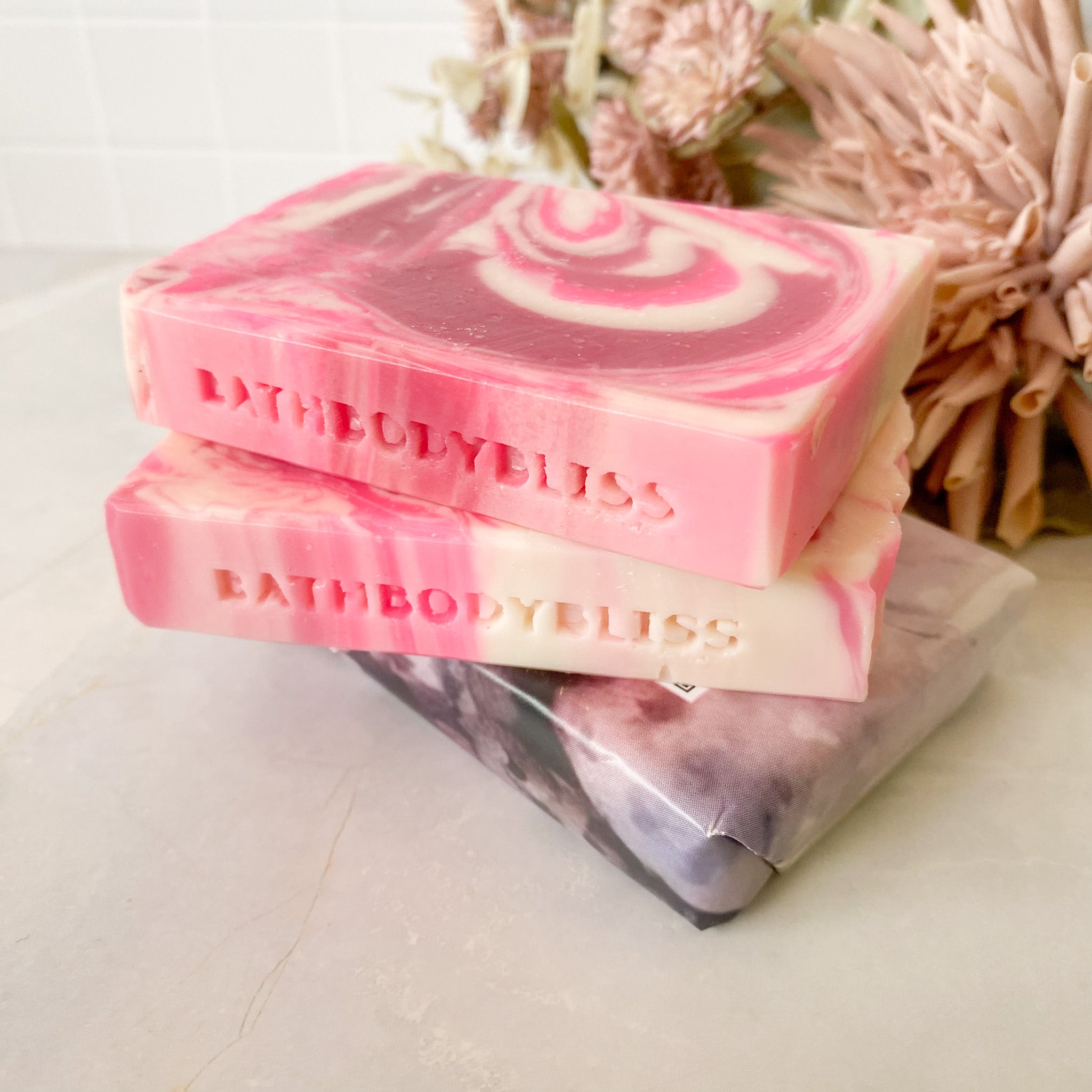 three pink and white soap bars stacked on a light surface