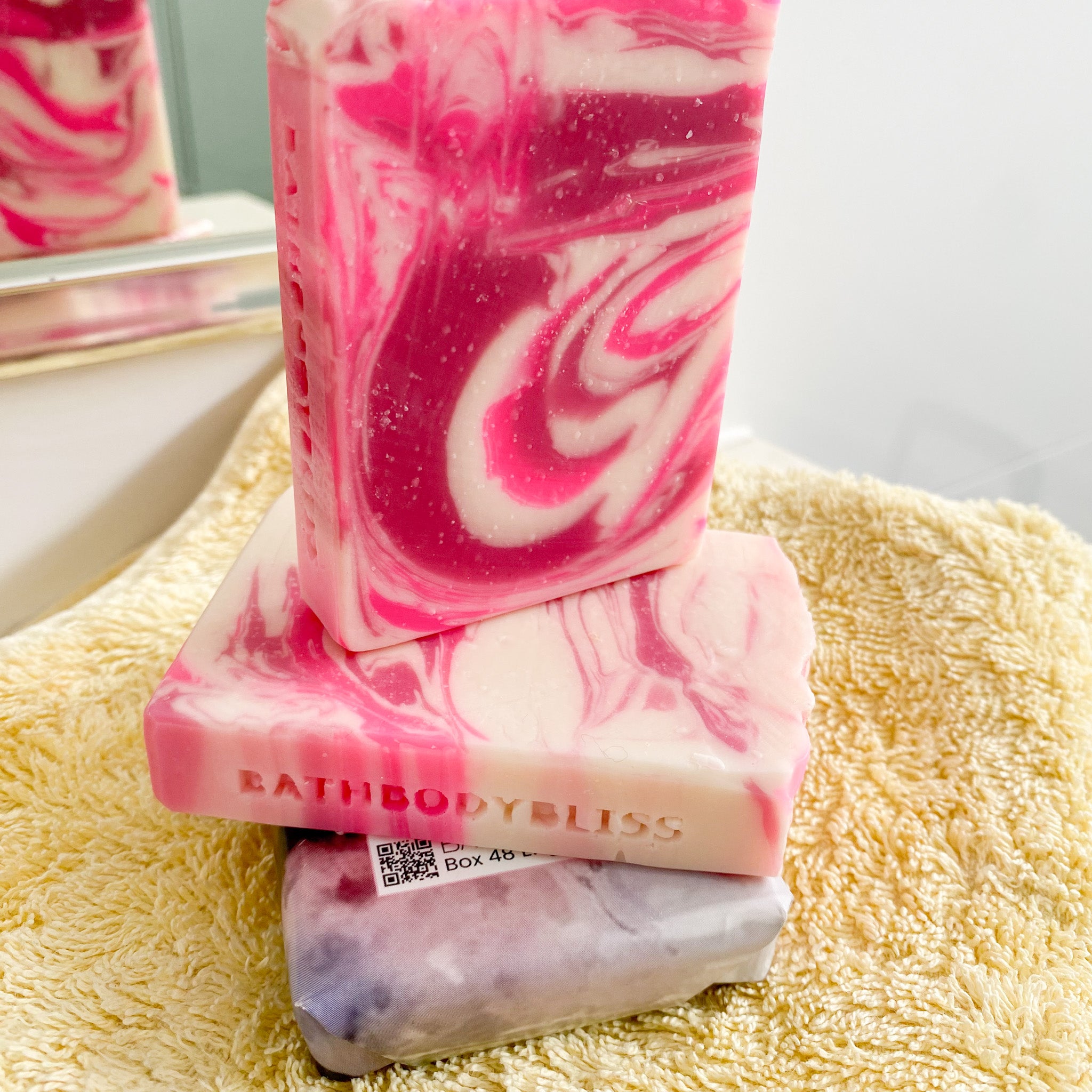stacked pink and white swirled soap bars on a yellow towel