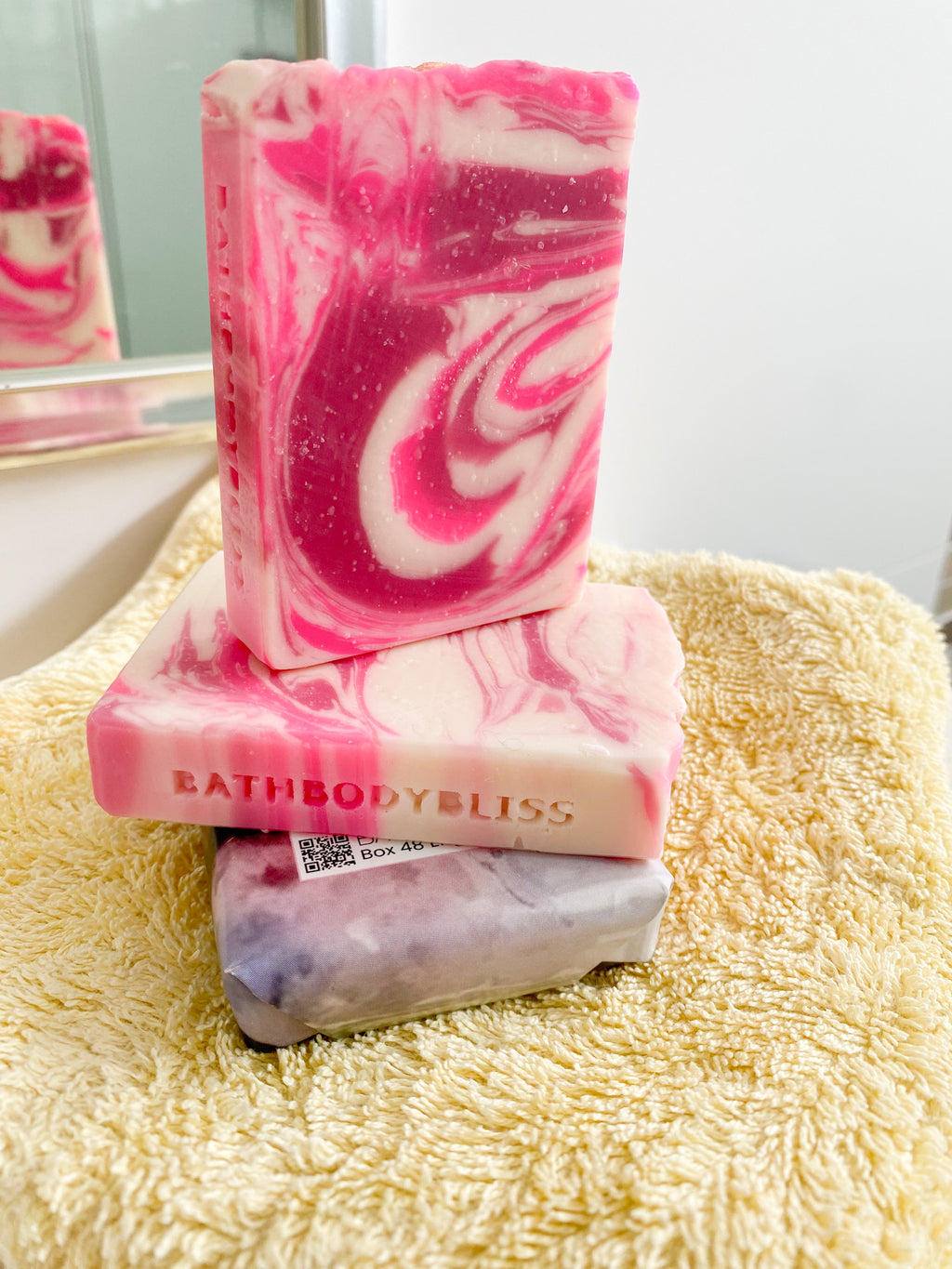 stacked pink and white swirled soap bars on a yellow towel