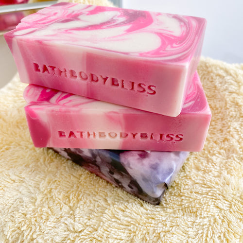 three pink and white swirled soap bars on a yellow towel