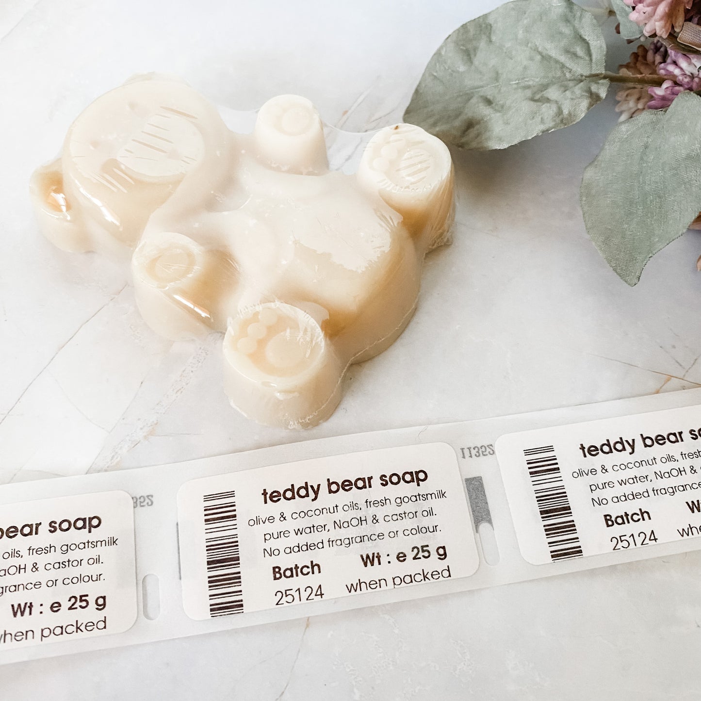 Teddy bear-shaped soap on a light background and printed soap labels