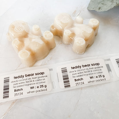 Two bear-shaped soap bars with a printed labels on a light background