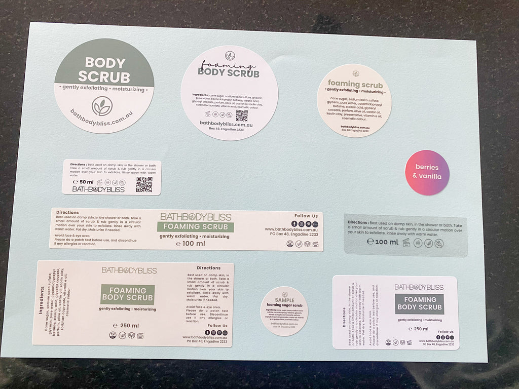 Sheet of Bath Body Bliss foaming body scrub labels on a blue surface