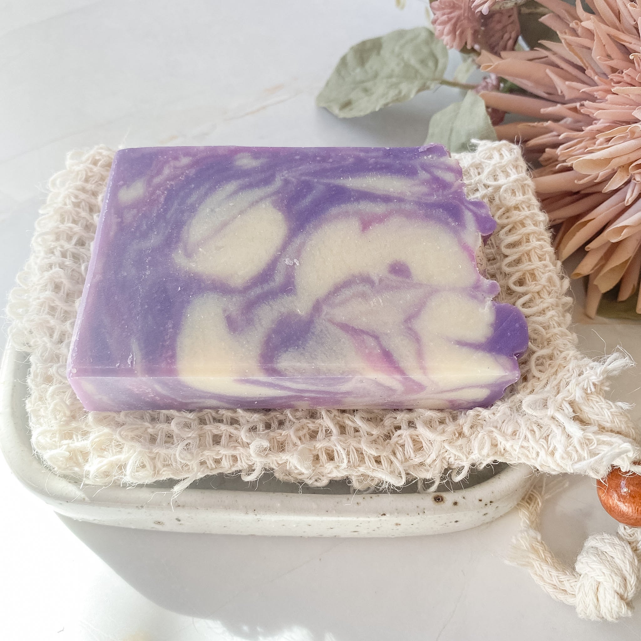 Purple and white swirled soap on a textured white surface with decorative elements.
