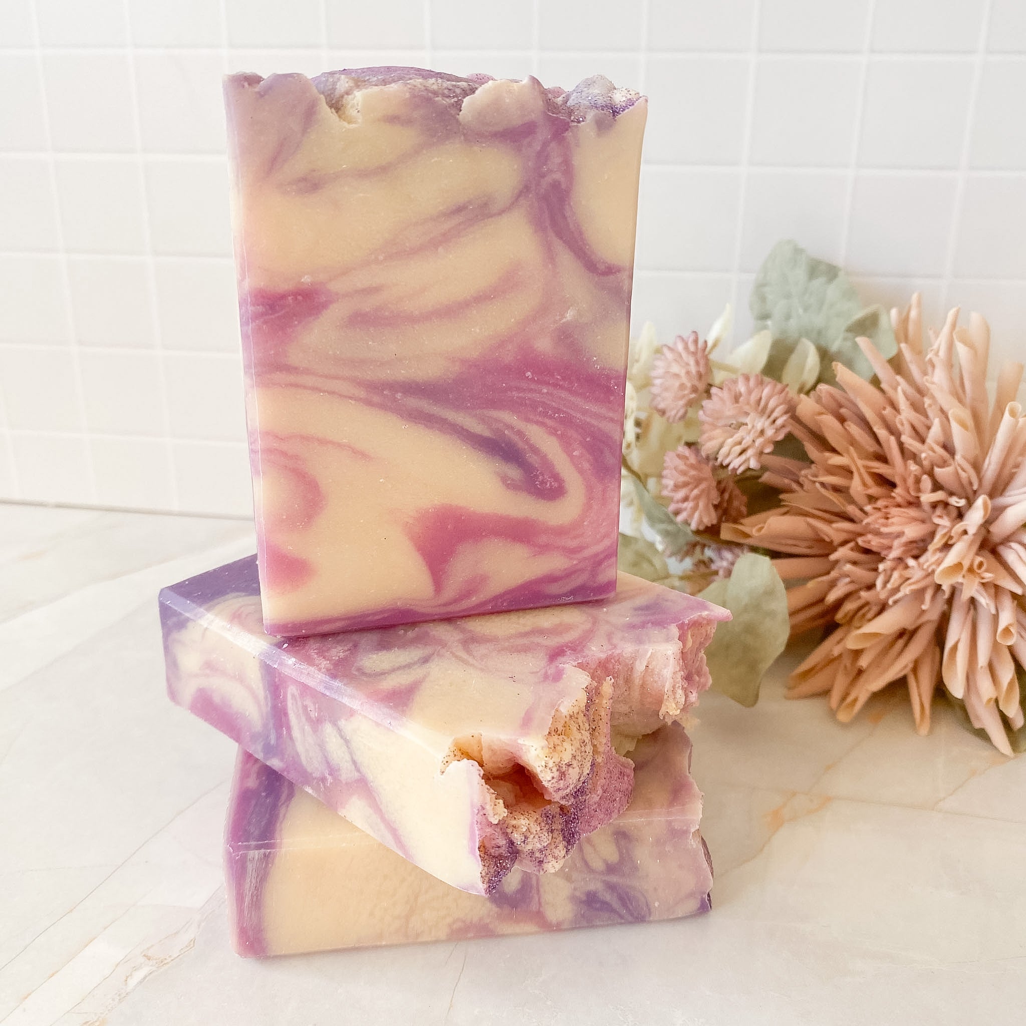 Three bars of swirled soap with floral elements on a white surface