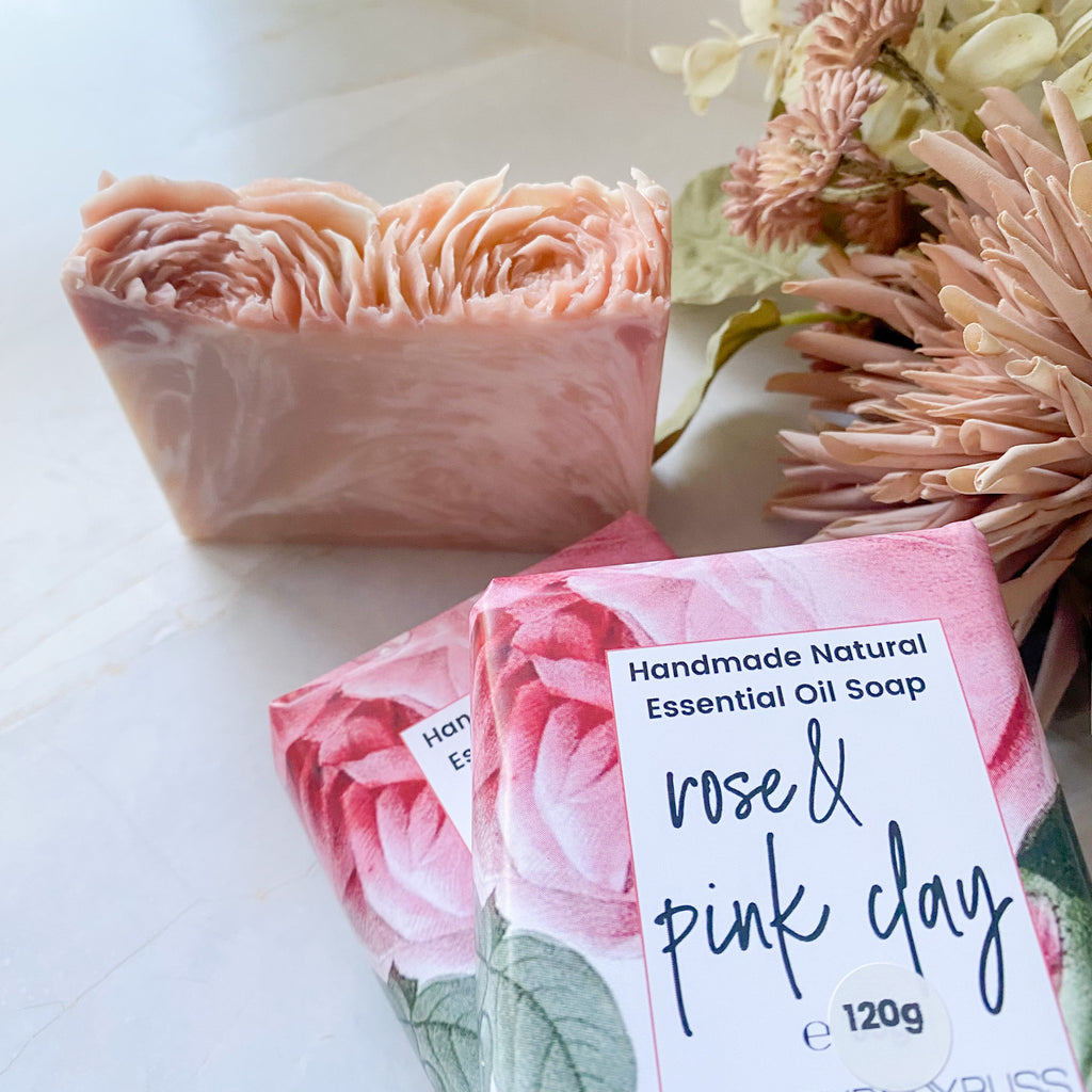 Handmade natural essential oil soap with a label on a white surface with flowers.