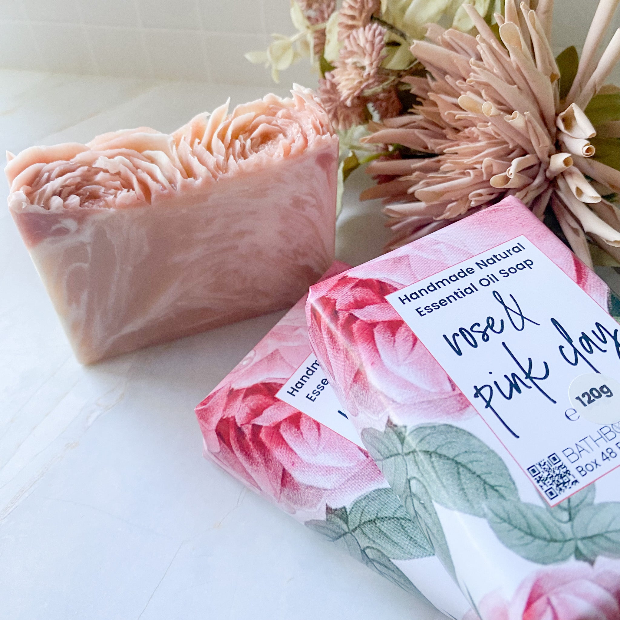 Handmade natural essential oil soap with floral packaging on a white surface