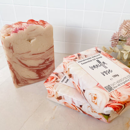 Three bars of soap, two wrapped and one unwrapped with a floral design, on a tiled bathroom floor.