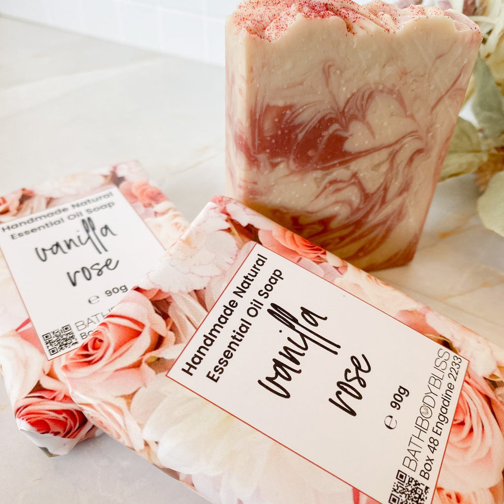 Three bars of 'Vanilla Rose' soap with floral packaging on a light surface.
