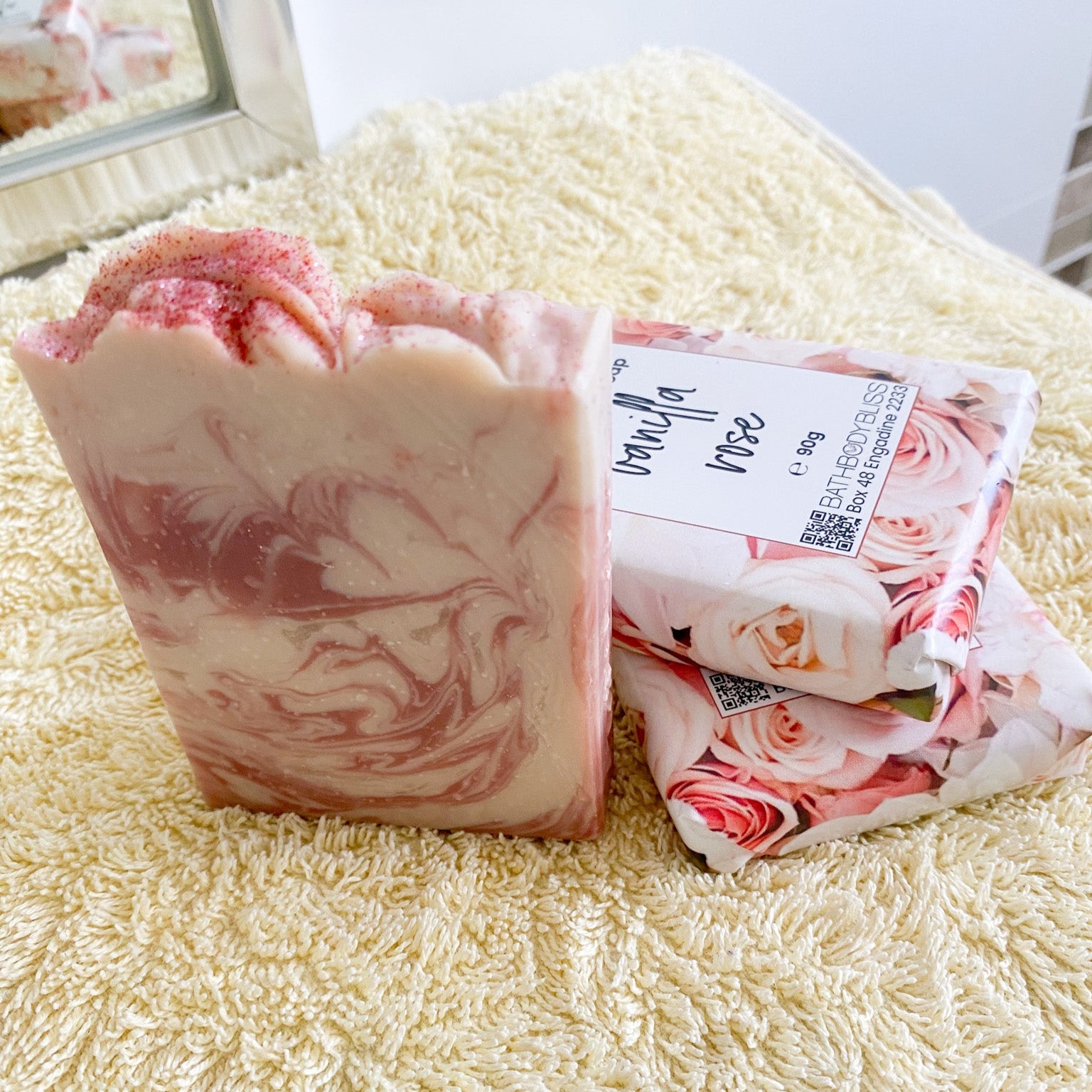 Pink marbled soap bar with floral packaging on a textured surface