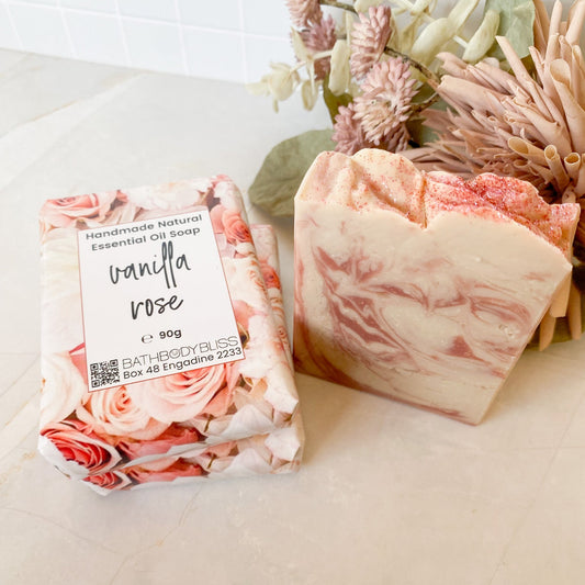 Three soap bars with floral packaging and a label on a light surface.