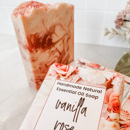 Handmade natural essential oil soap bar with 'vanilla rose' packaging on a light background.