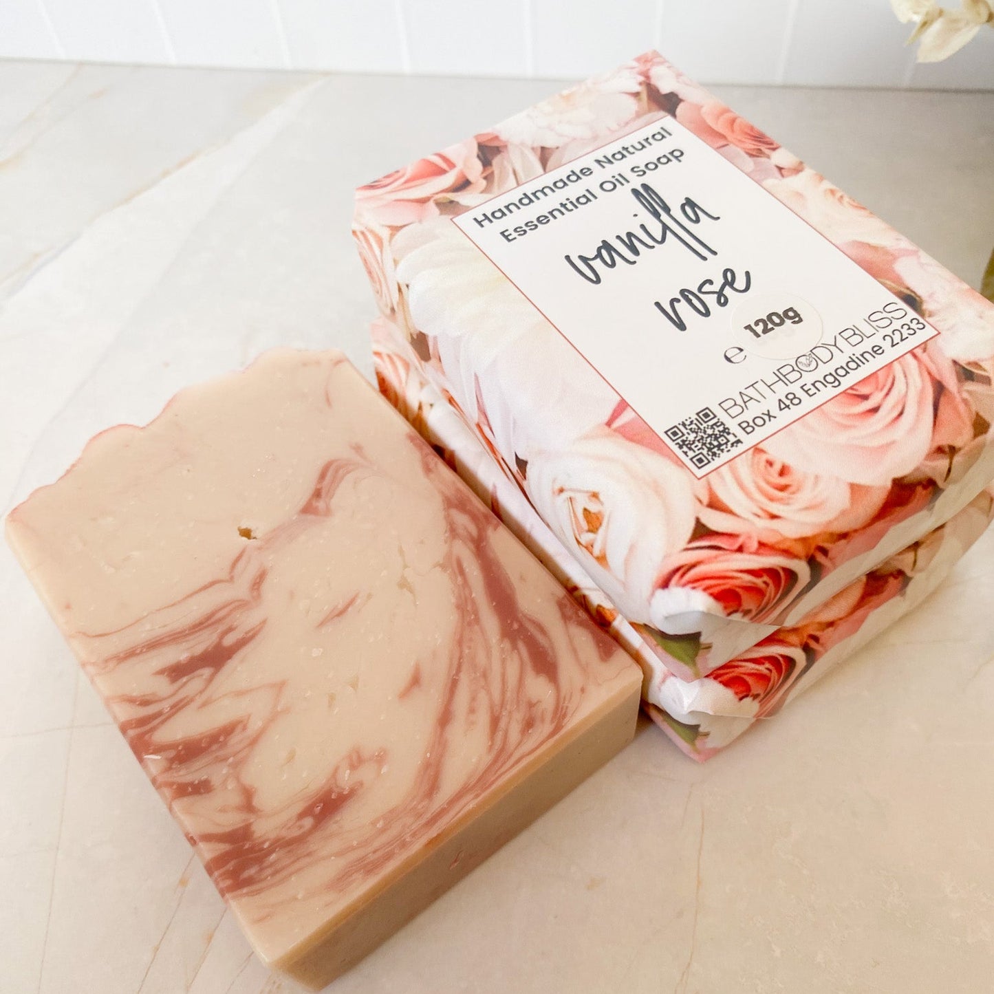 Marbled soap bar and floral soap packaging on a marble surface