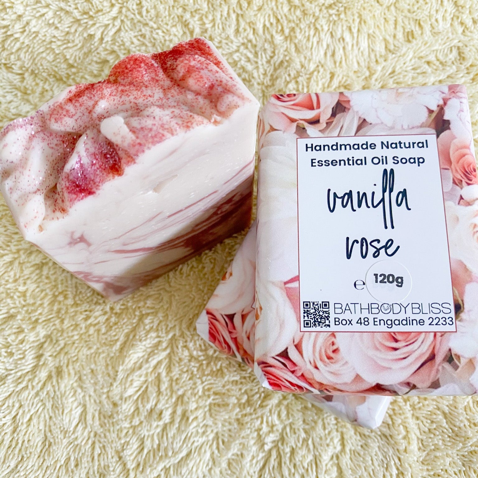 Handmade natural essential oil soap labeled 'Vanilla Rose' on a textured yellow towel surface.