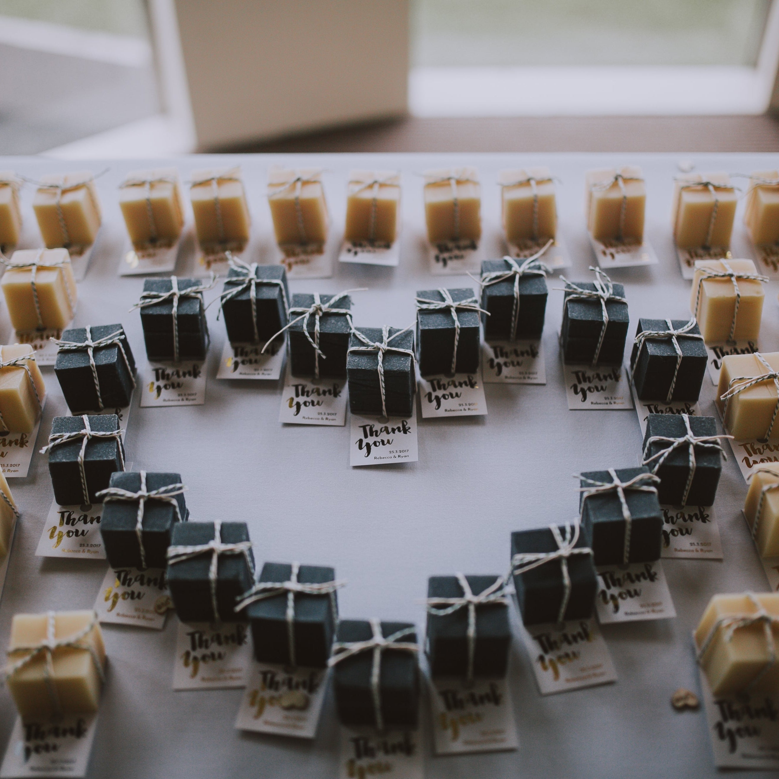 handmade soap favours in charcoal black & lemongrass natural colours, arranged in a heart formation.