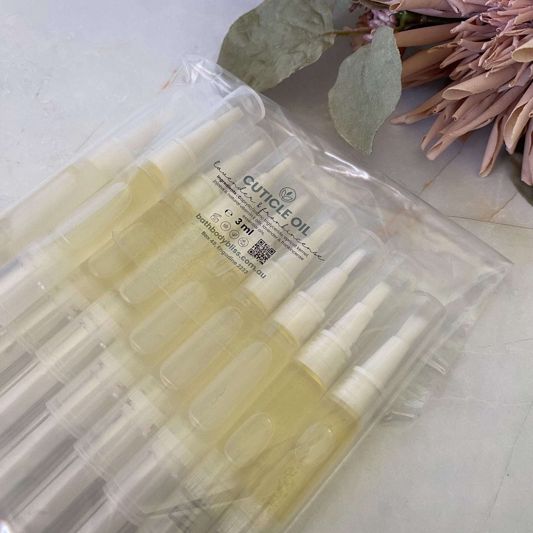 Pack of cuticle oil applicator pens with a clear plastic packaging on a light surface.