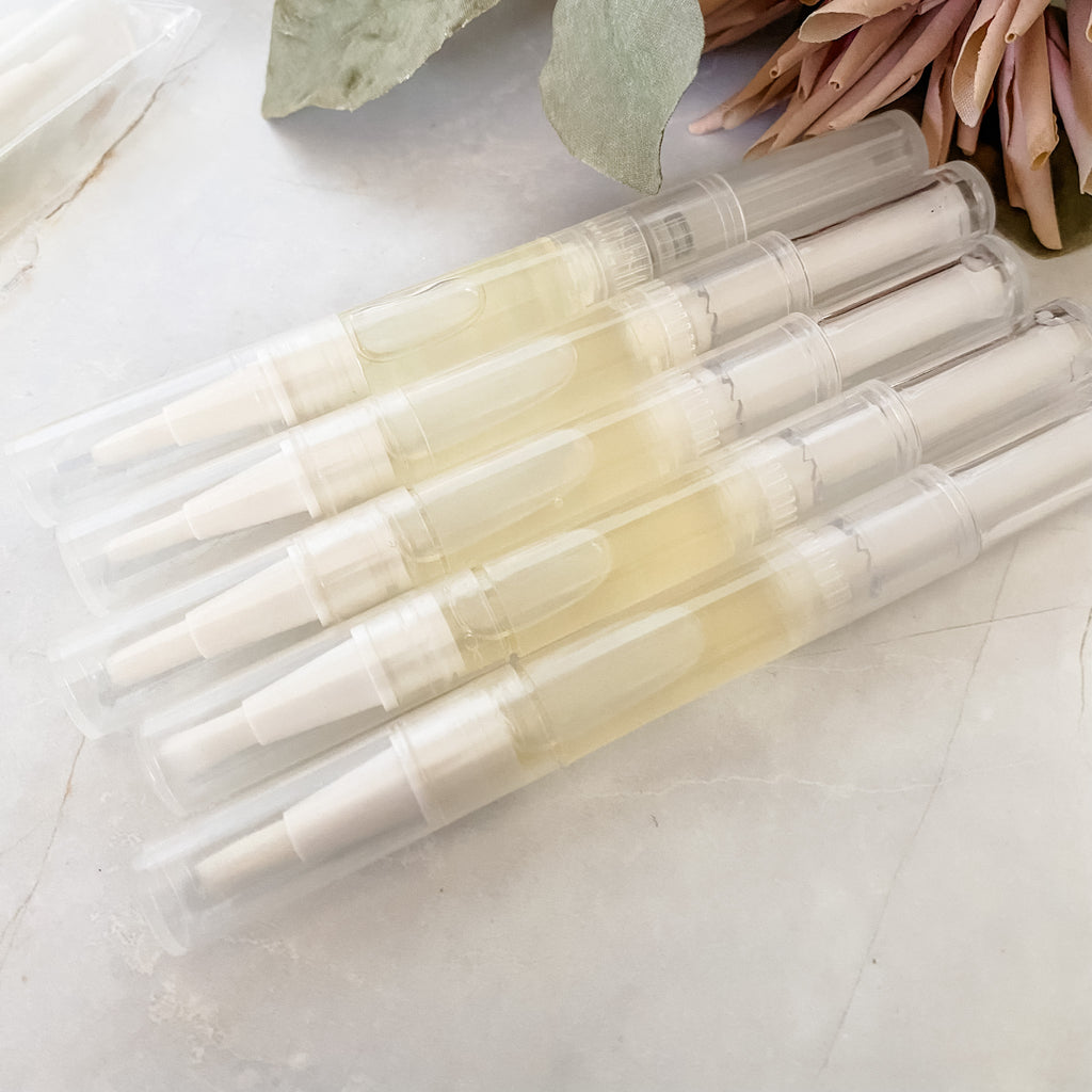 five twist up pens of cuticle oil on a light surface