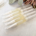 five twist up pens of cuticle oil on a light surface