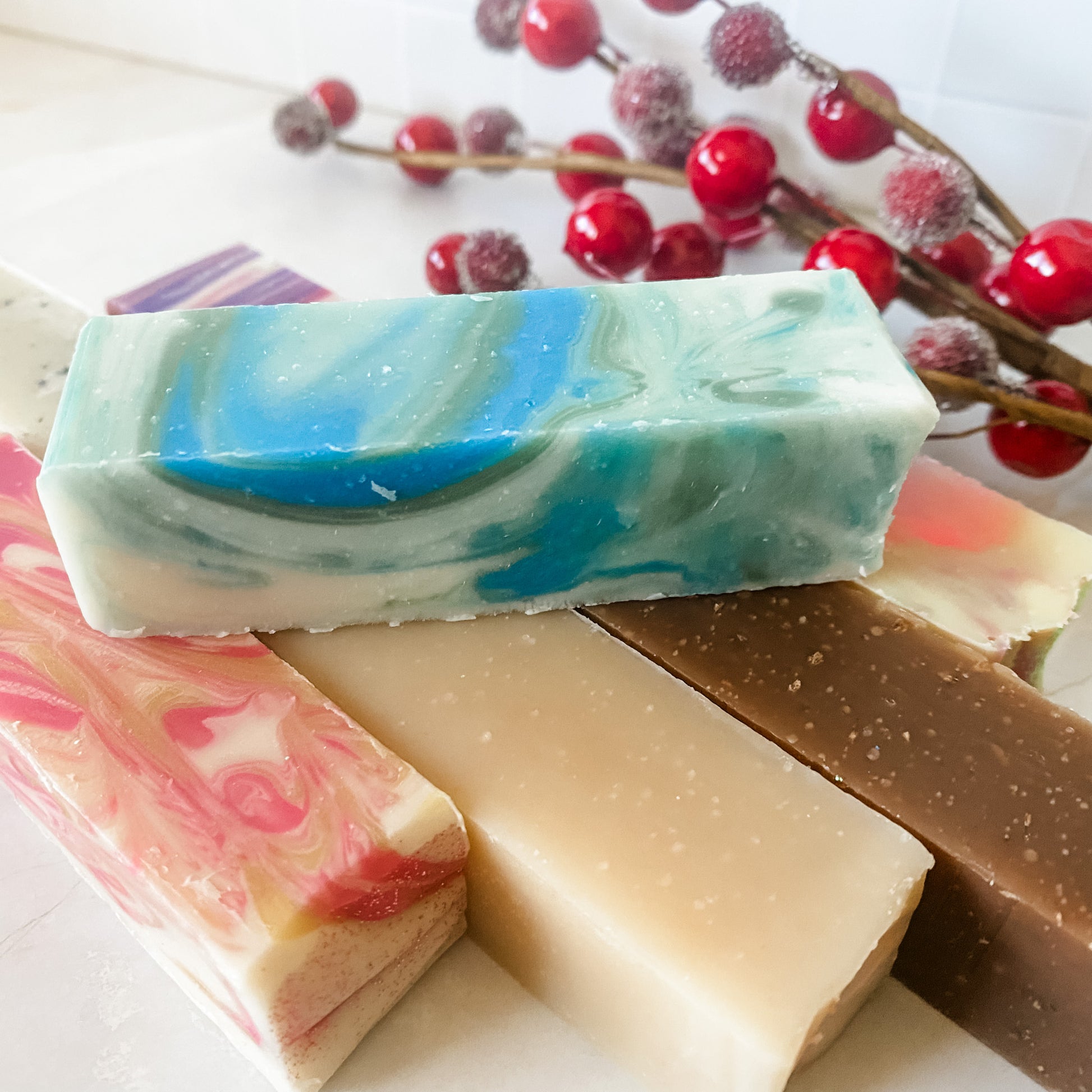 Stack of colorful soap bars with a branch of red berries in the background