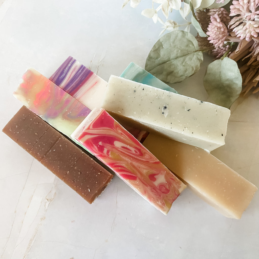 Assorted colorful soap bars on a light surface with decorative elements.