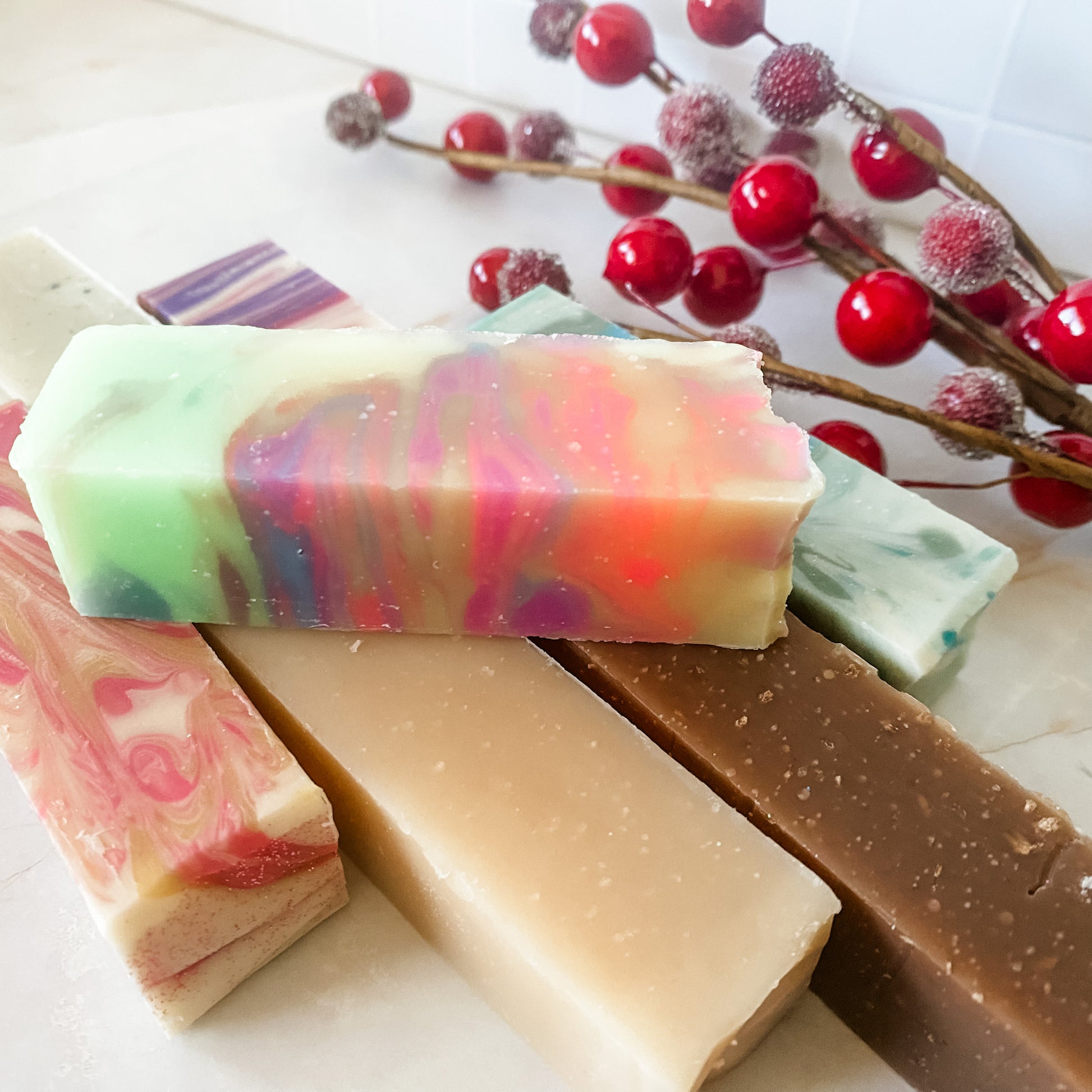 Colorful soap bars with a branch of red berries on a light background