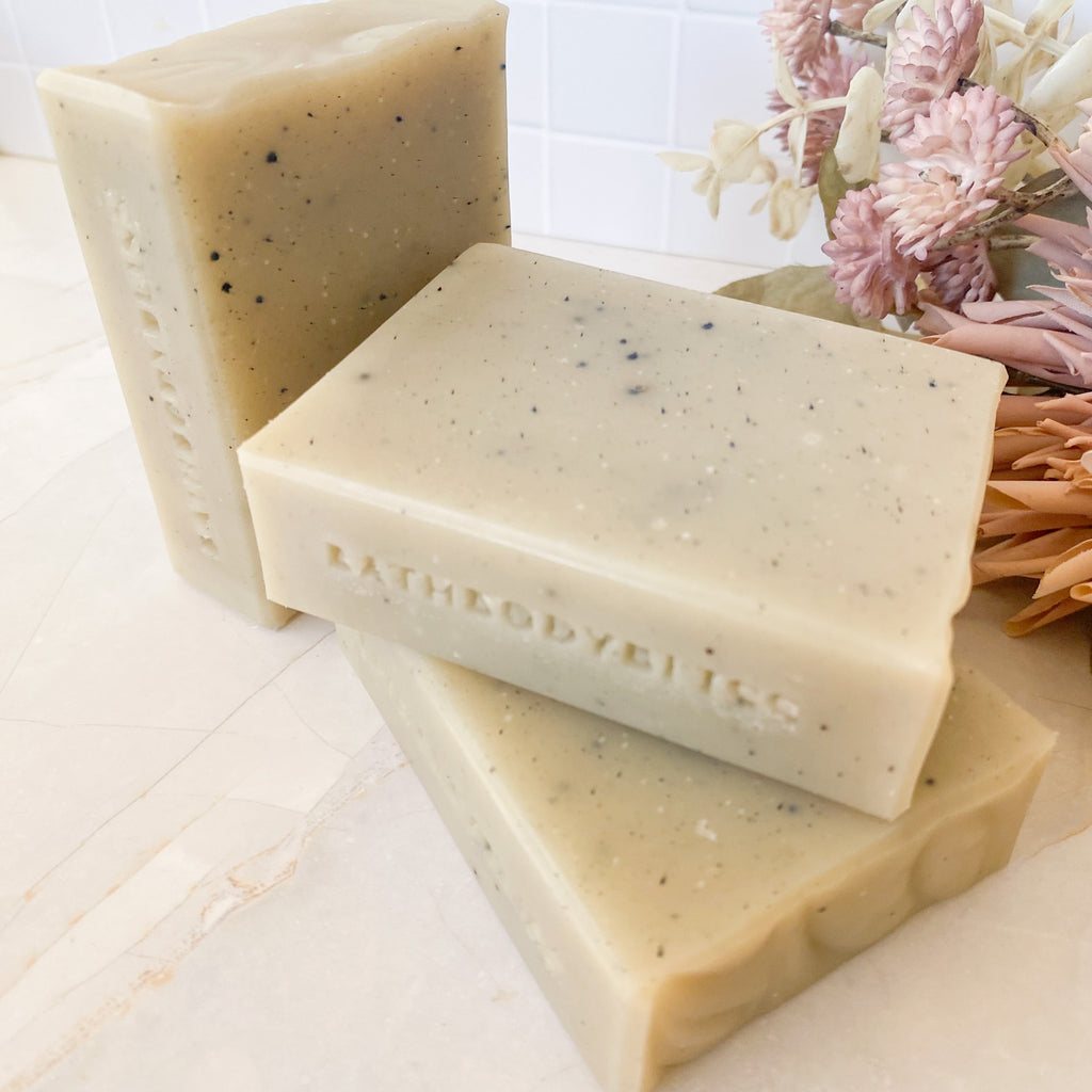 Three bars of soap with 'bathbodybliss' branding on a light background with flowers.