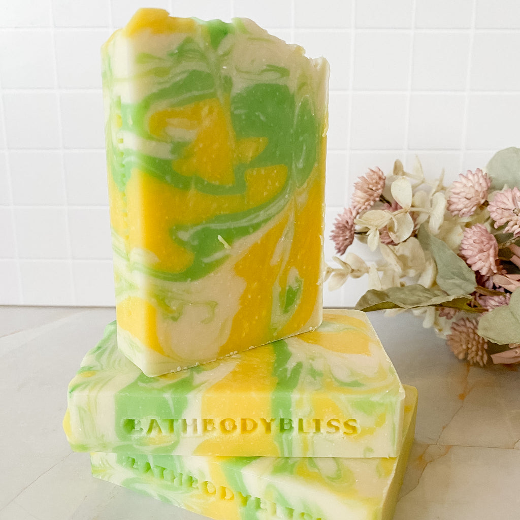 Two bars of yellow and green marbled soap with 'BathBodyBliss' branding on a white surface.