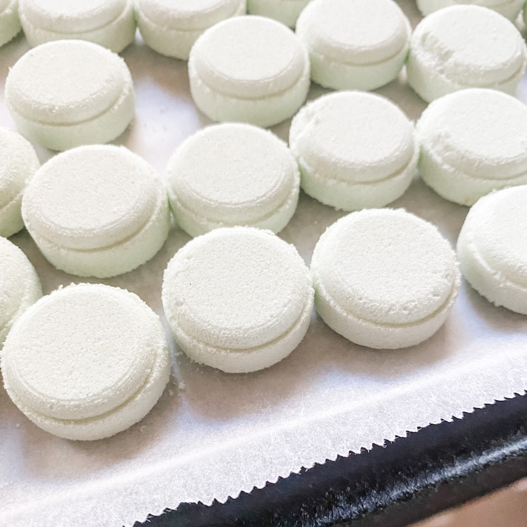 lots of small white round bathbomb style tabs on a lined tray