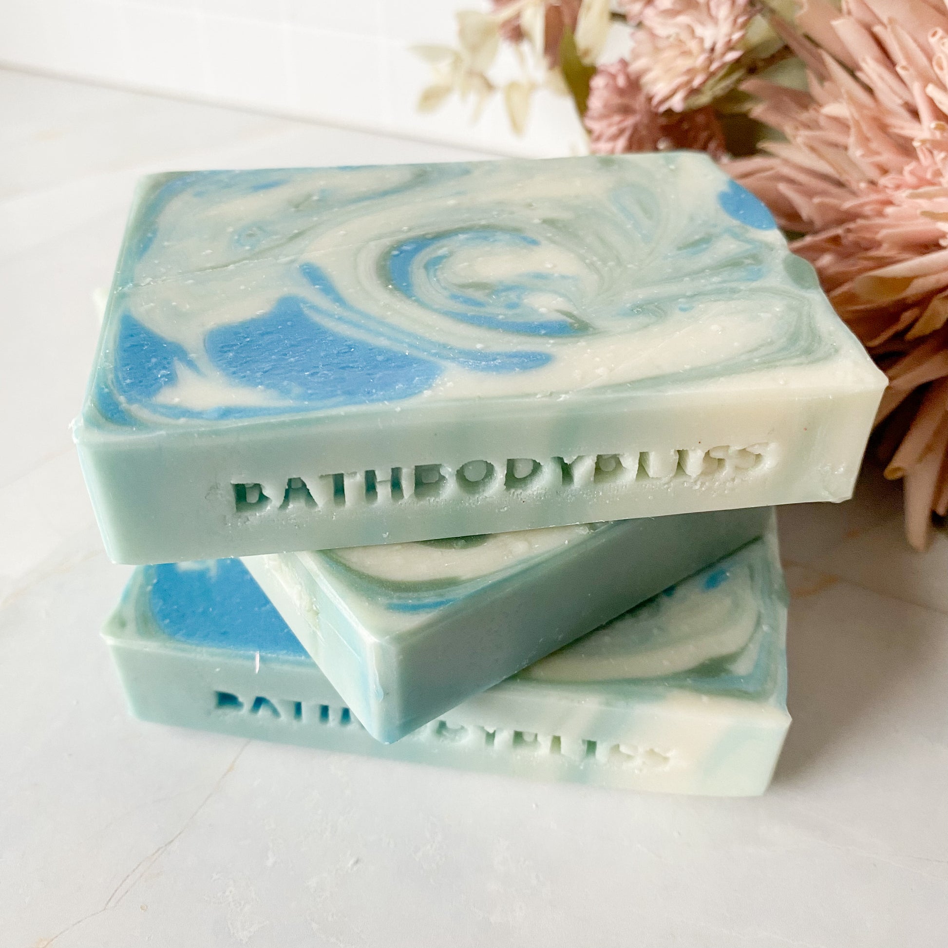 Three swirled blue and white soap bars with bathbodybliss branding on a light surface.