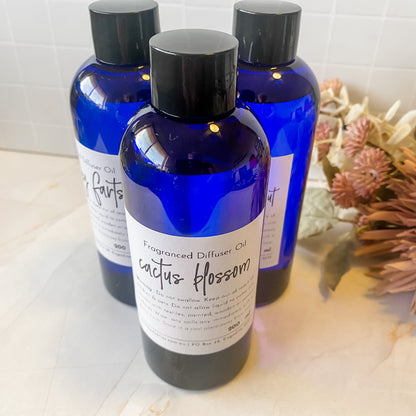 Three blue bottles of diffuser oil on a light surface with a blurred background.
