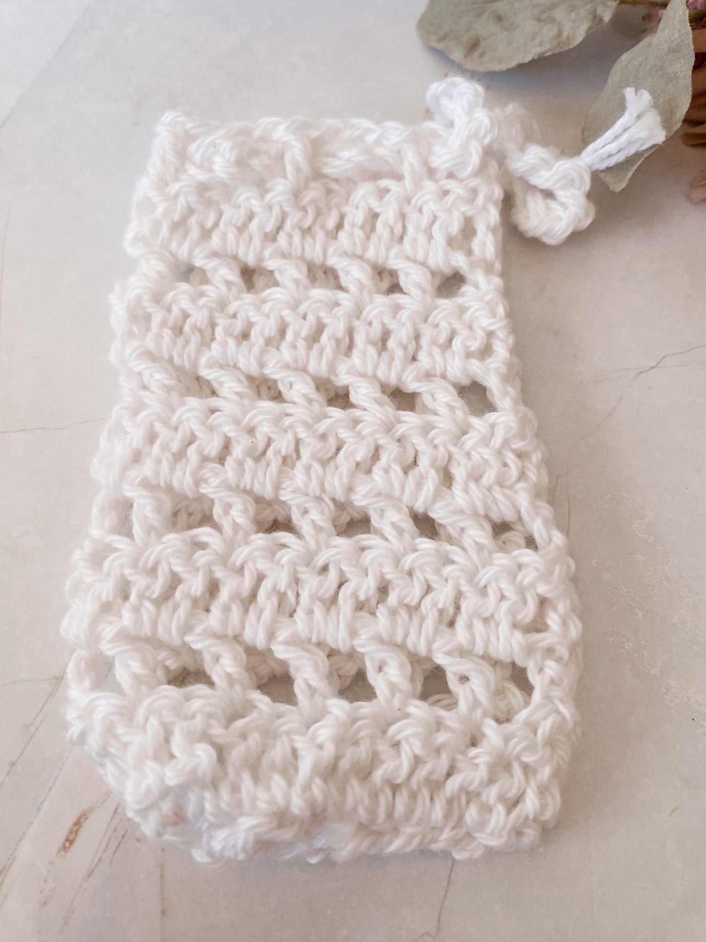 White crocheted soap saver sack on a light wooden surface