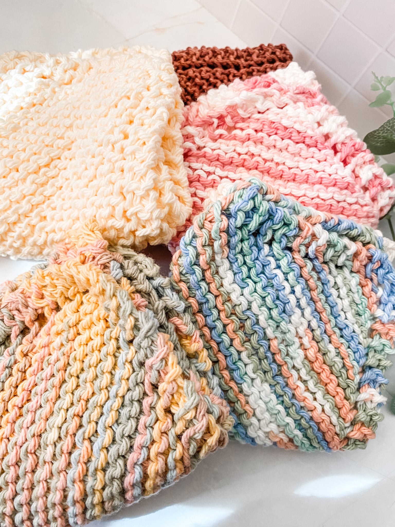 Set of colorful hand-knitted dishcloths on a white surface