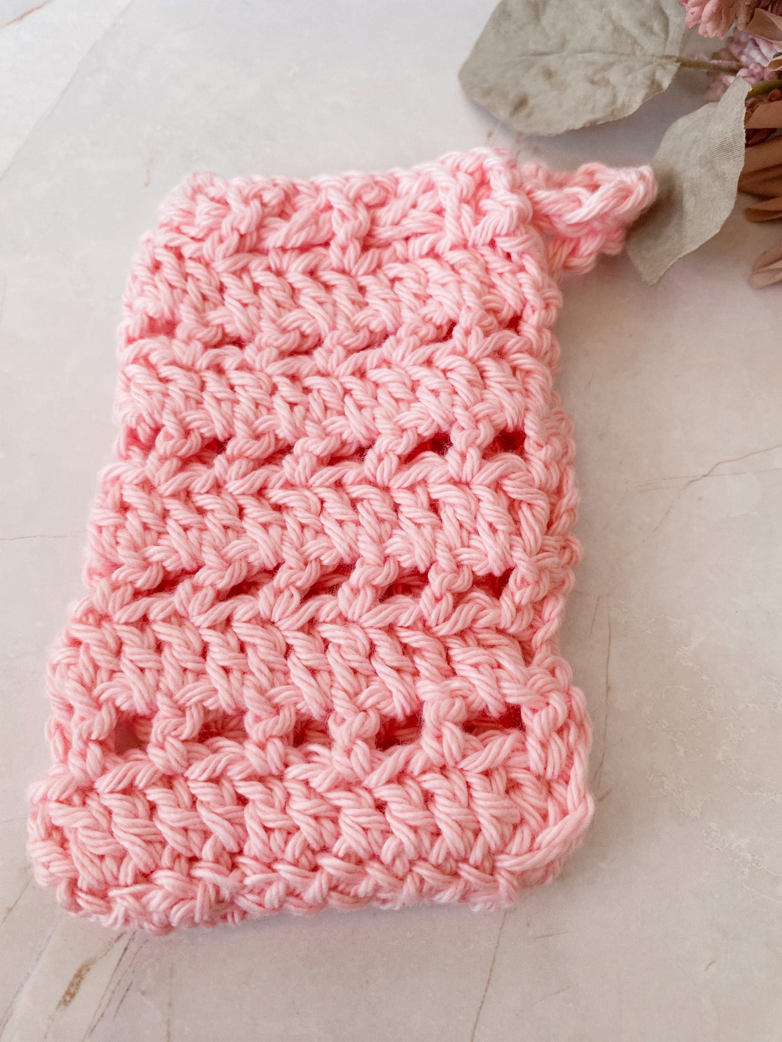 Pink crocheted soap saver sack on a light surface