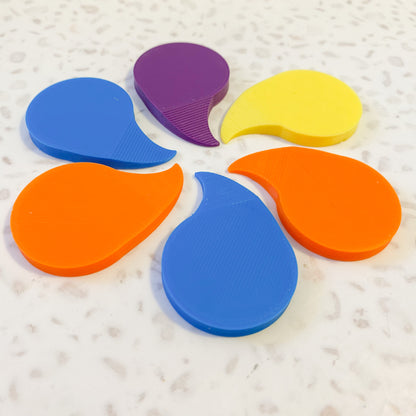 six brightly coloured 3D printed plastic shrink wrap openers arranged in a circle on a pale speckled background